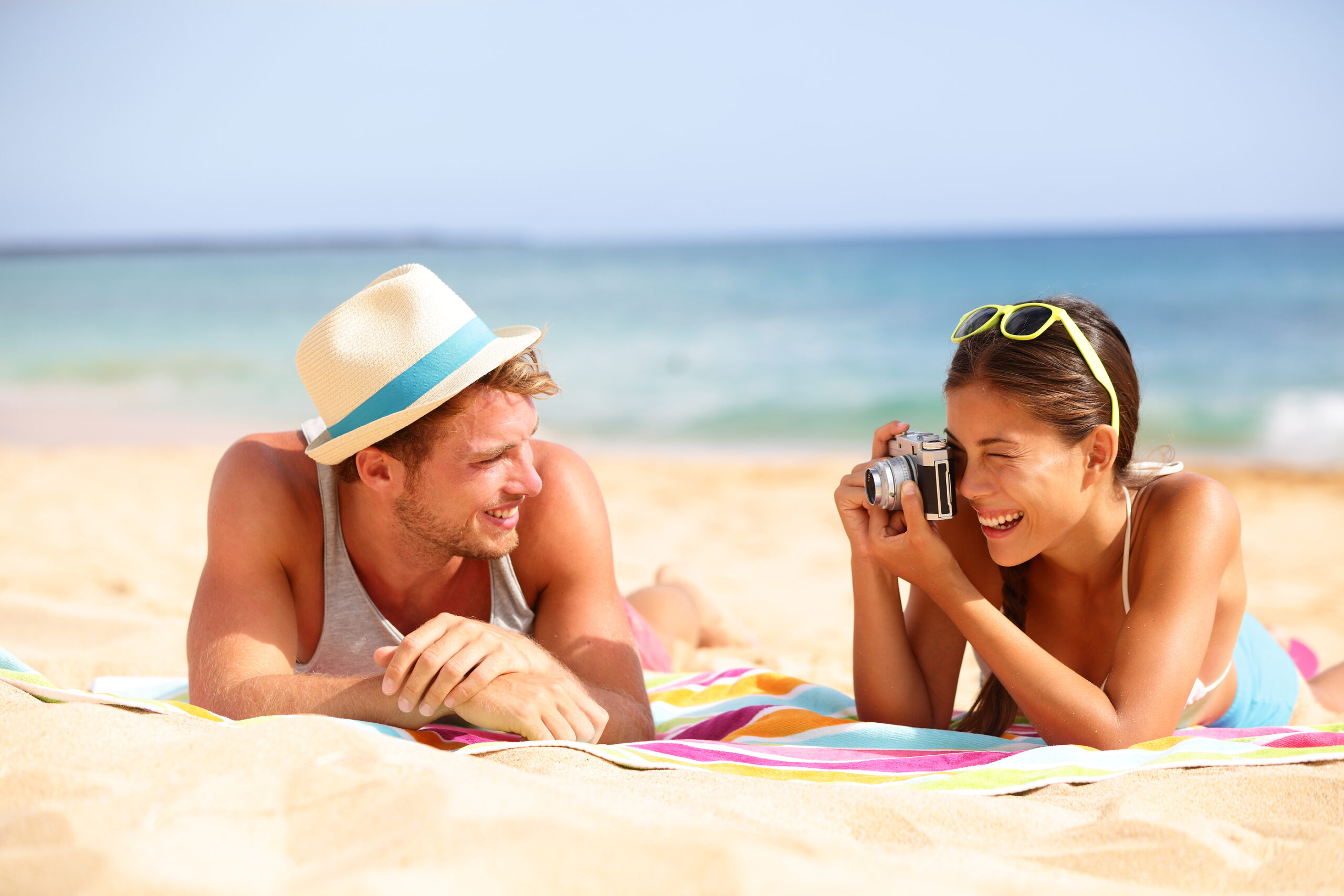 Beach fun couple travel. Woman taking photo picture of man smili