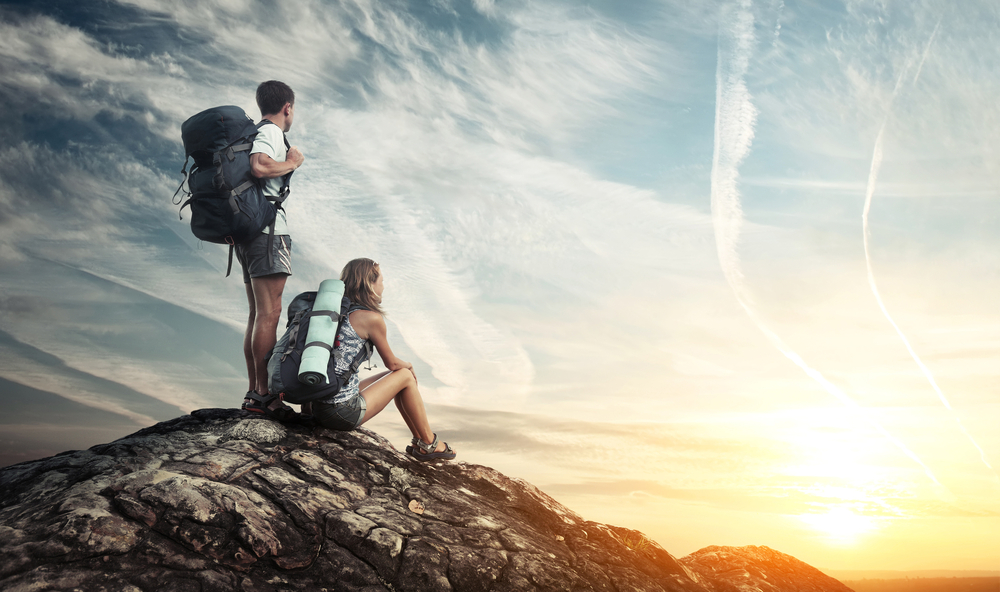 Two,Tourists,With,Backpacks,Enjoying,Sunset,On,Top,Of,A